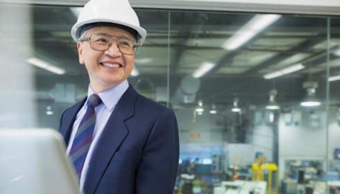 工廠內的經理微笑著使用筆記本電腦
